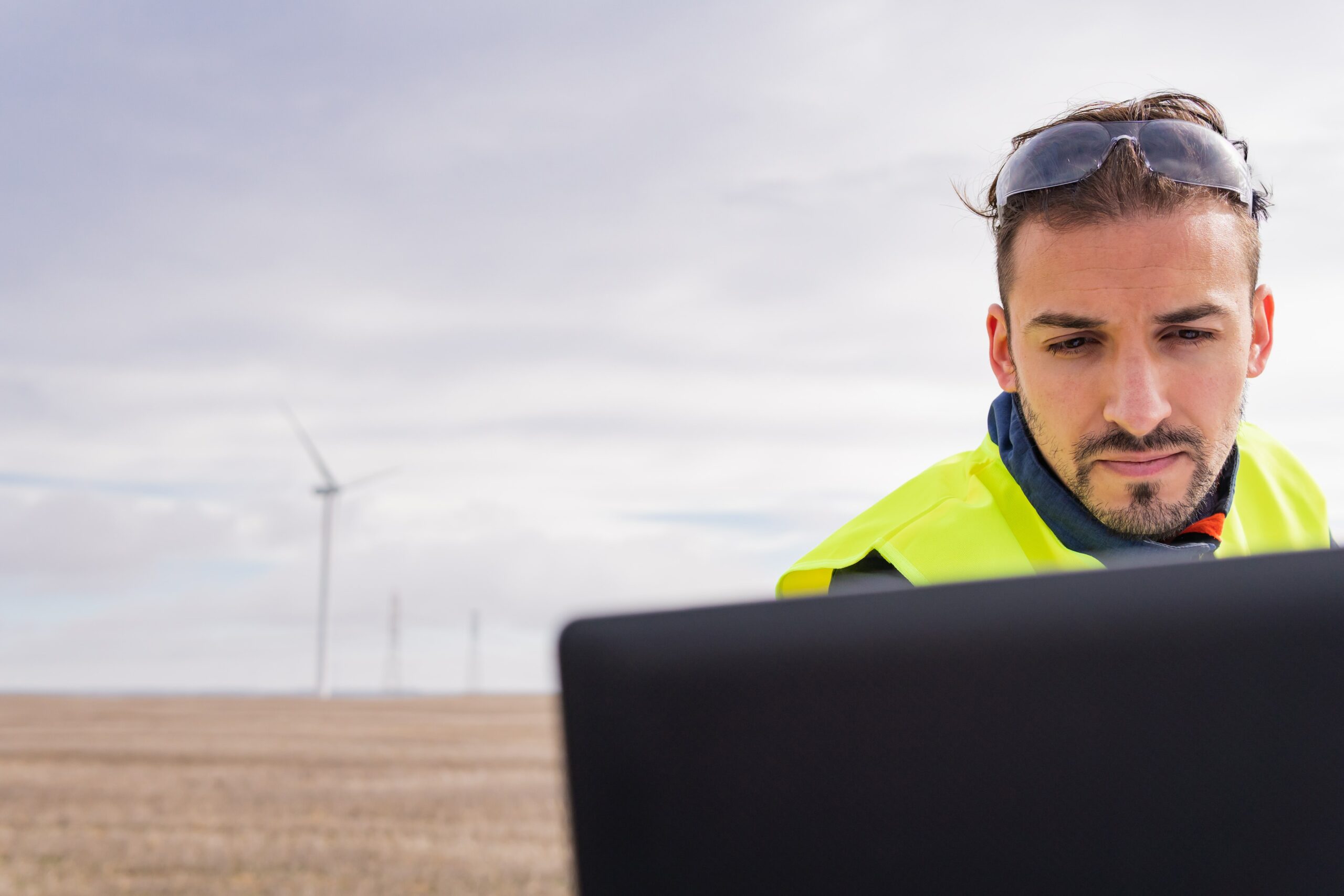 man works with laptop in wind farm